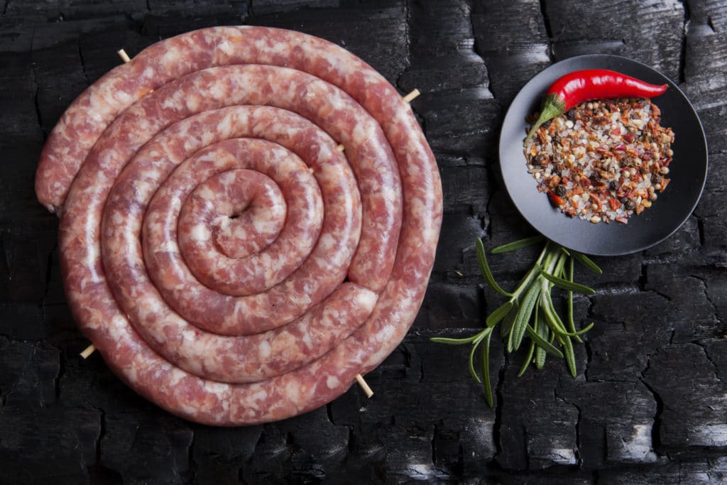Freshly Made Raw Spiral Sausages In Skins On A Black Background Of